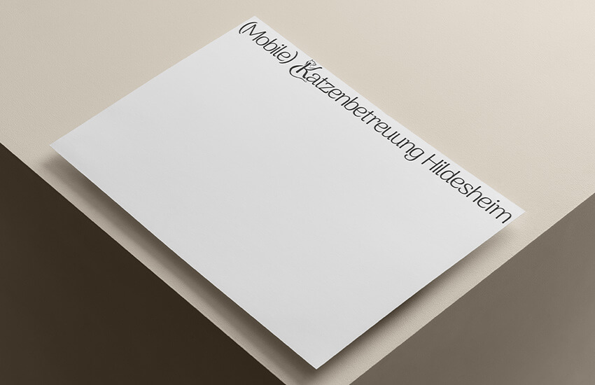 Eine Logoversion für die (Mobile) Katzenbetreuung Hildesheim. Die Bildmarke zeigt ein K um das eine Katze ist, die ihre Pfote in die Höhe streckt. Die Bildmarke ist integriert. Man sieht es auf einem Blatt Papier auf einem Tisch.
