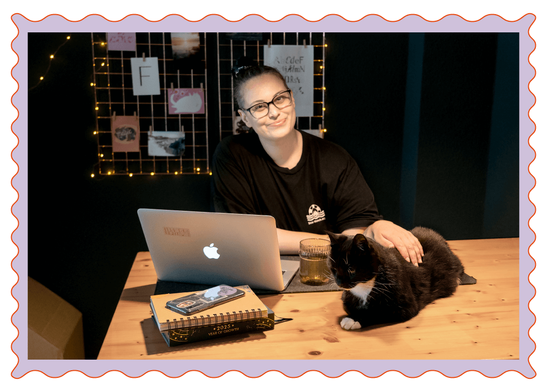 Vanessa und ihre Katze Lizzie sitzen am Schreibtisch und schauen in die Kamera