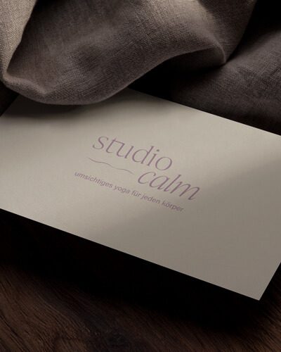 Die Visitenkarte vom Studio Calm, auf einem Holztisch mit einem Tuch.